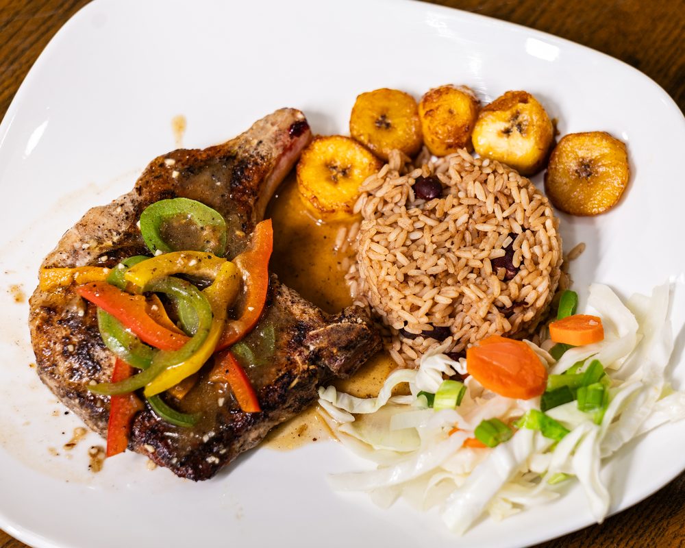 Jerk pork chop grilled with peppers over rice and peas