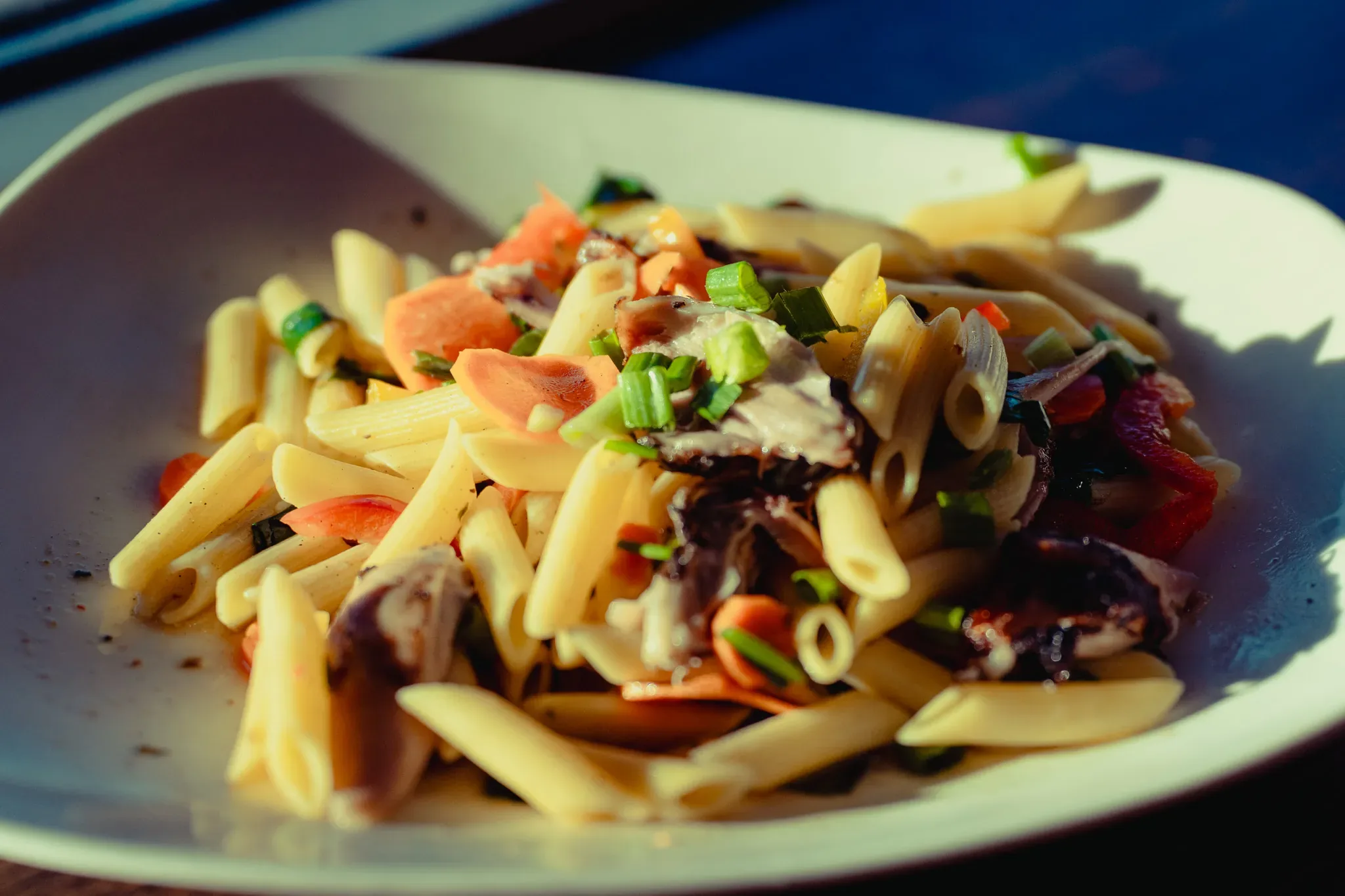 Close-up of rasta pasta with peppers, carrots and scallions