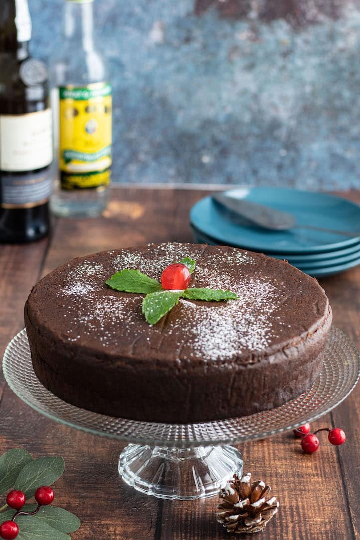 A Jamaican black cake, dark and dense, dusted with sugar and topped with a cherry and mint